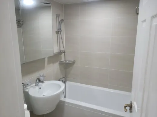 A fully renovated bathroom with a bathtub, new tiling and shower set
