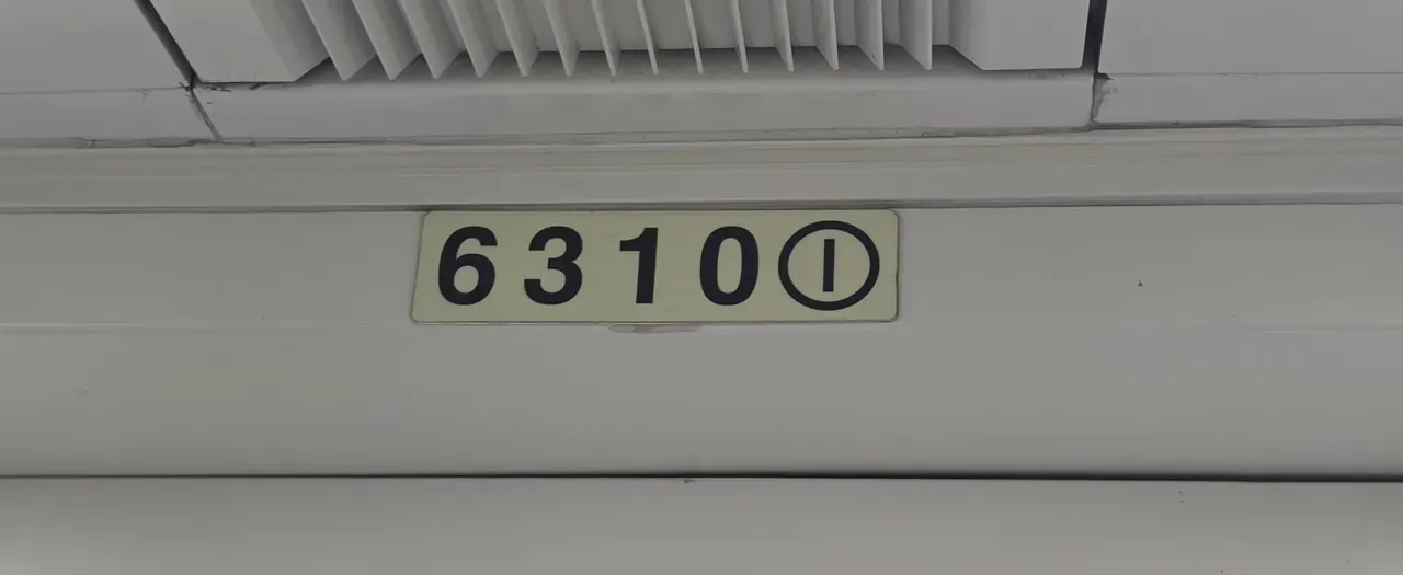 A small plate above a Seoul subway train door reading 6310 with a circled 1, giving the car number and door number